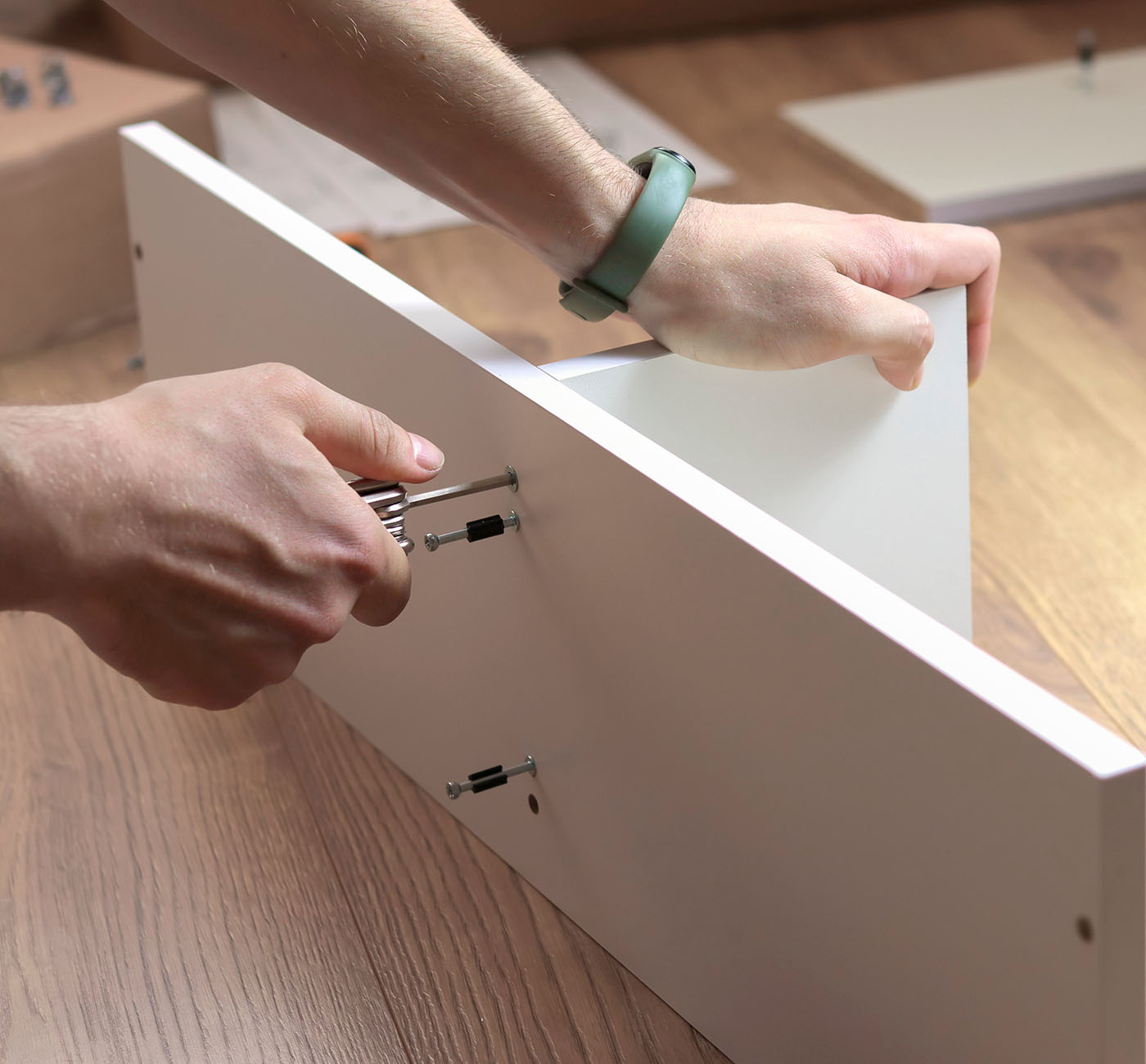 Flat Pack Assembly this picture shows a person putting together flat pack furniture with a screwdriver