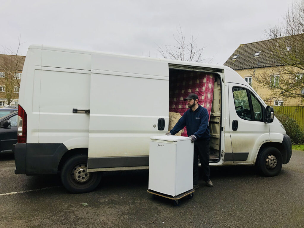 Man and Van this image shows one of our drivers unloading a free standing fridge from the van