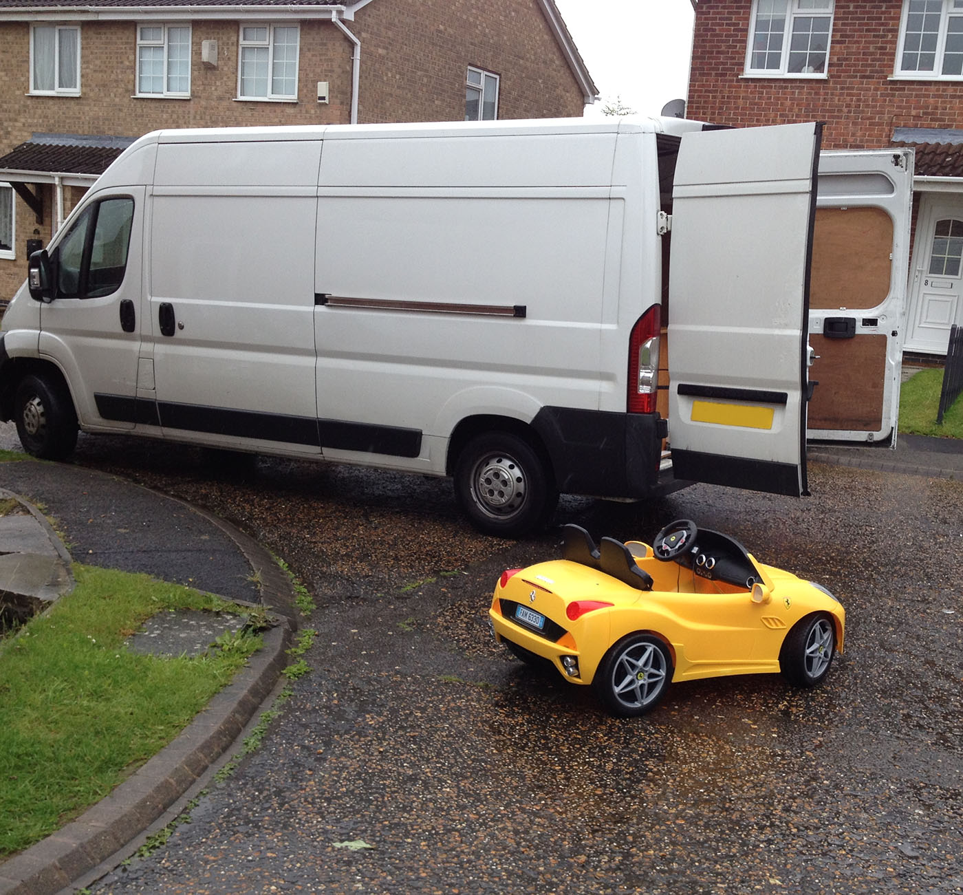 Removals this picture shows ones of our moving vans with the back doors open and a bright yellow childs ride in car in front of it